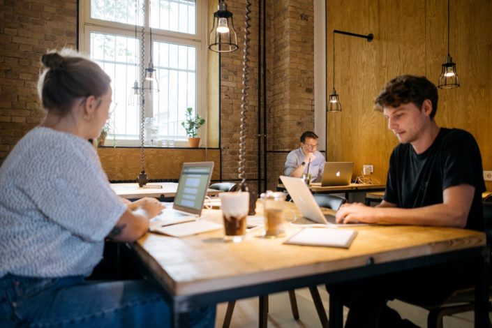 Flexibler Arbeitsplatz in Friedrichshain Coworker sitzen zusammen und arbeiten an unterschiedlichen Projekten